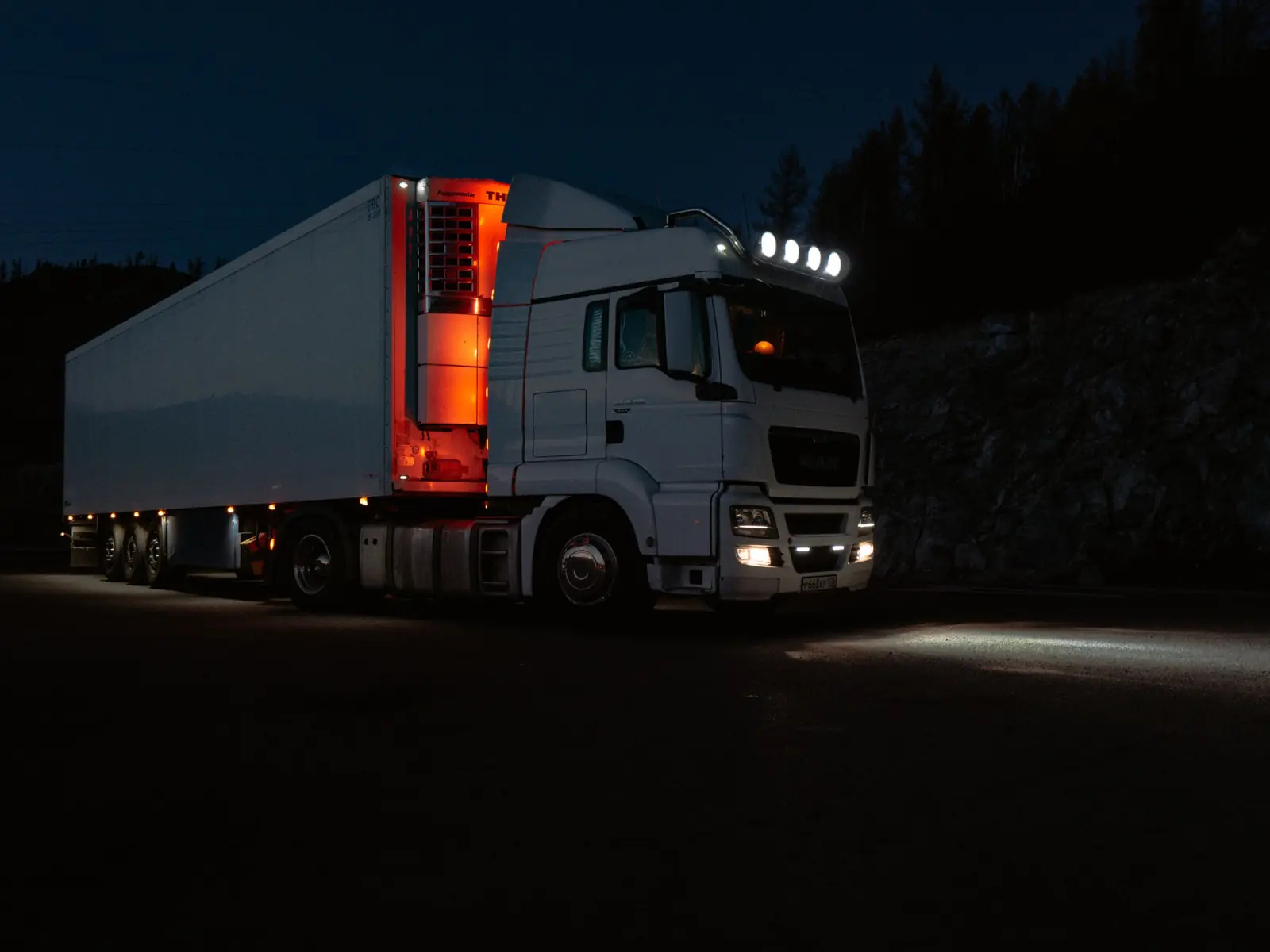 Camion frigorific alb, oprit noaptea, cu farurile aprinse