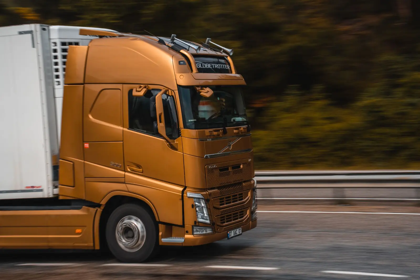 Camion portocaliu pe autostradă, în mișcare